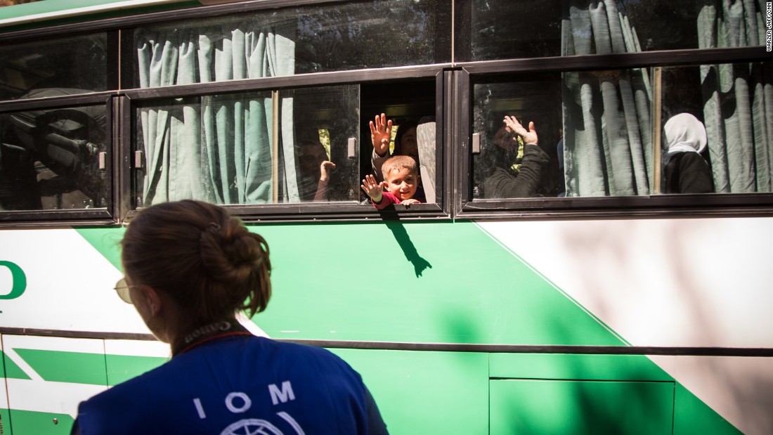 Women and children wave goodbye to relatives before their journey to Germany.