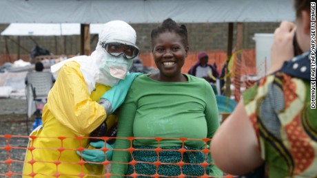 A health worker, wearing Personal Protective Equipment (PPE), and a woman pose on September 7, 2014 inside the high-risk area at Elwa hospital in Monrovia, which is run by the non-governmental  international organization Medecins Sans Frontieres (Doctors without Borders -- MSF). US President Barack Obama said in an interview aired on September 7 the US military would help in the fight against fast-spreading Ebola in Africa, but warned it would be months before the epidemic slowed. The tropical virus, transmitted through contact with infected bodily fluids, has killed 2,100 people in four countries since the start of the year -- more than half of them in Liberia.   AFP PHOTO / DOMINIQUE FAGET        (Photo credit should read DOMINIQUE FAGET/AFP/Getty Images)