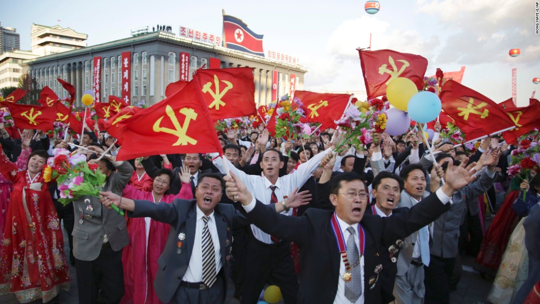 North Koreans parade with flags of the ruling Workers&#39; Party.