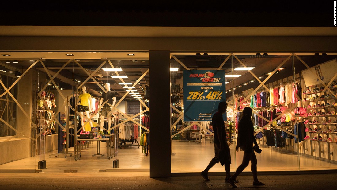 People in Puerto Vallarta walk past a shop with taped windows on Thursday, October 22.