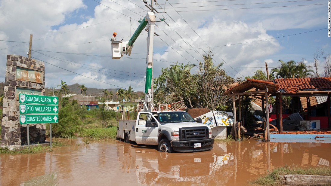 Men work to restore downed power lines on October 24 in Melaque.