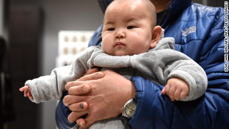 This picture taken on January 19, 2015 shows a Chinese baby in the arms of his father at a furniture store in Beijing.  China&#39;s working-age population continued to fall in 2014, the government said on January 20, as Beijing struggles to address a spiralling demographic challenge made worse by its one-child policy.    AFP PHOTO/GOH CHAI HIN        (Photo credit should read GOH CHAI HIN/AFP/Getty Images)