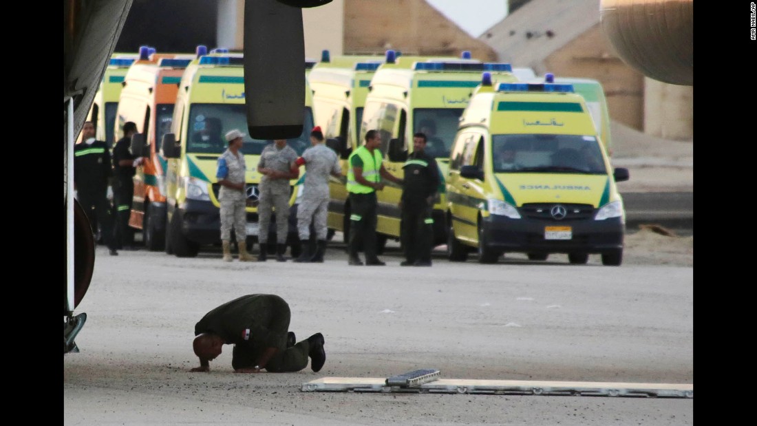 An Egyptian soldier prays as emergency workers prepare to unload bodies of victims at a military airport north of Suez, Egypt, on October 31.