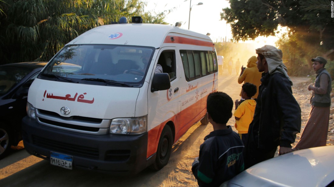 Villagers watch an ambulance as it drives to unload bodies on October 31.