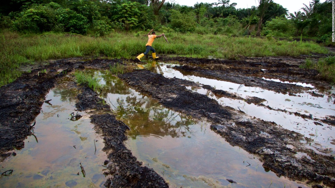 A man jumps across water dirtied by oil pollution in Ogoniland, Nigeria.  