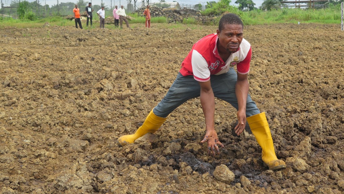 A man shows how the land is contaminated with oil pollution.  