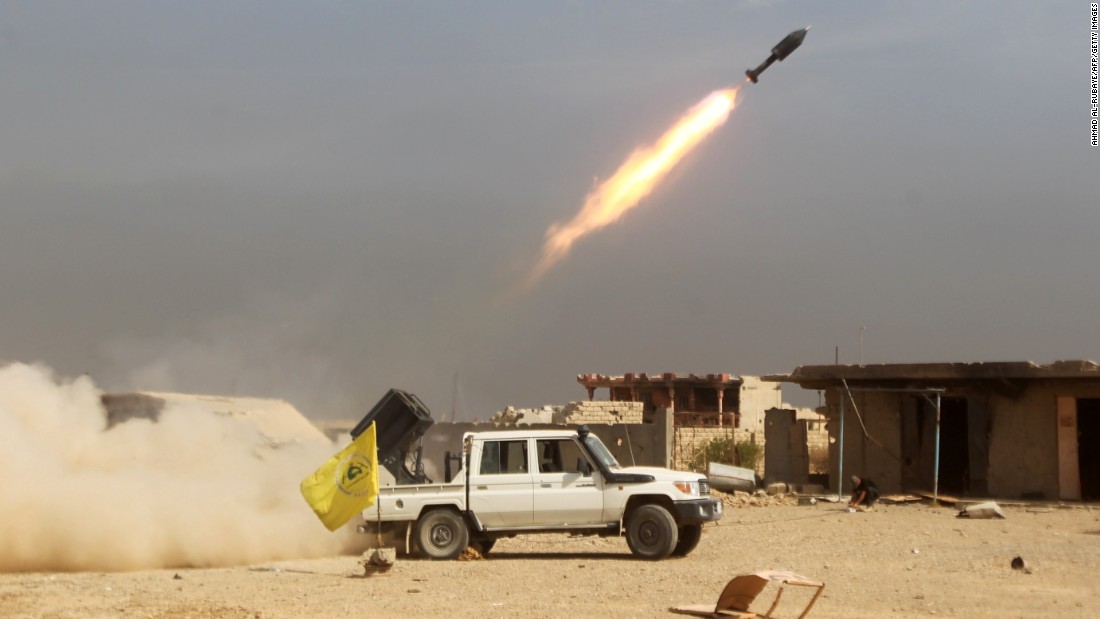 Shiite fighters, fighting alongside Iraqi government forces, fire a rocket at ISIS militants as they advance toward the center of Baiji, Iraq, on Monday, October 19.