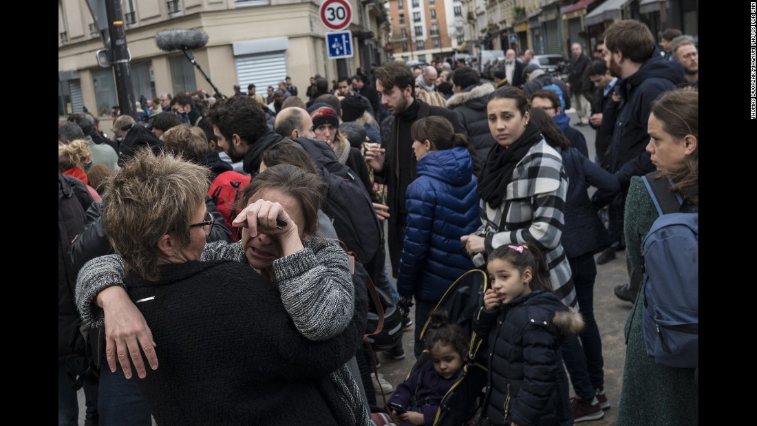 A crowd gathers on November 14 outside Le Petit Cambodge, where more than a dozen people were killed.