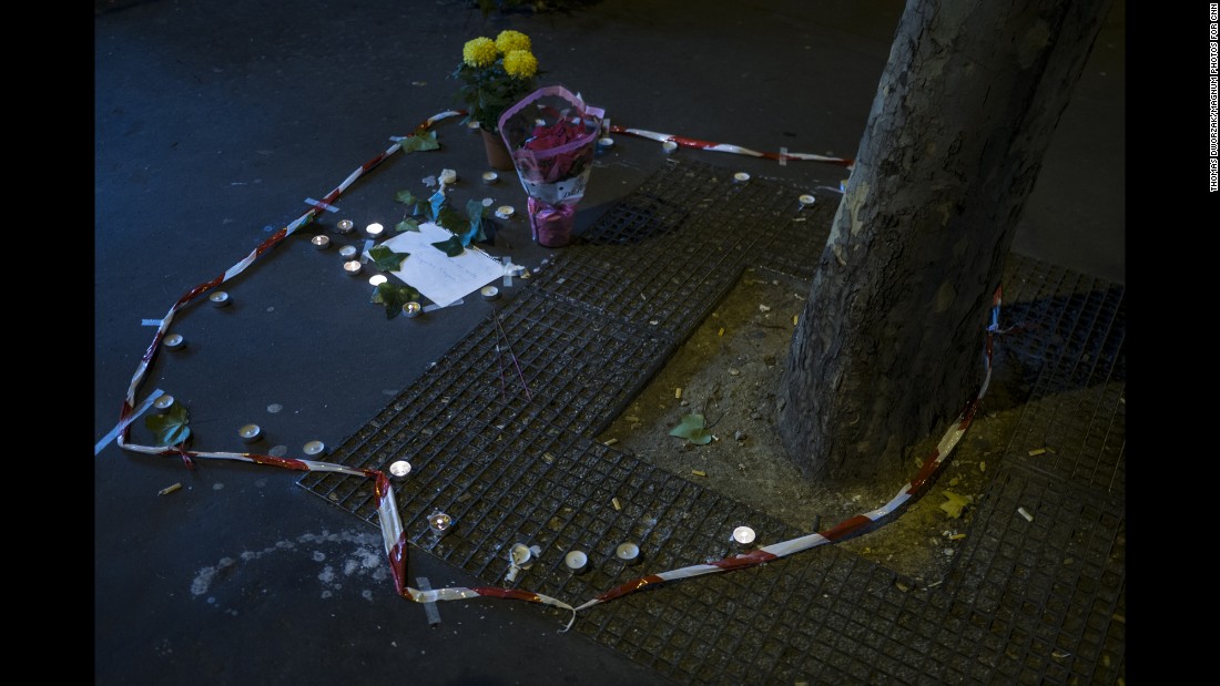Candles and flowers are seen on November 14 at the spot where a victim died on the Rue de la Fontaine au Roi. Five people were killed in a shooting outside a bar in Paris&#39; 11th district, according to prosecutor Francois Molins.