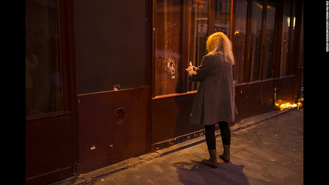 A woman takes a picture of a window shattered by bullets on November 14.