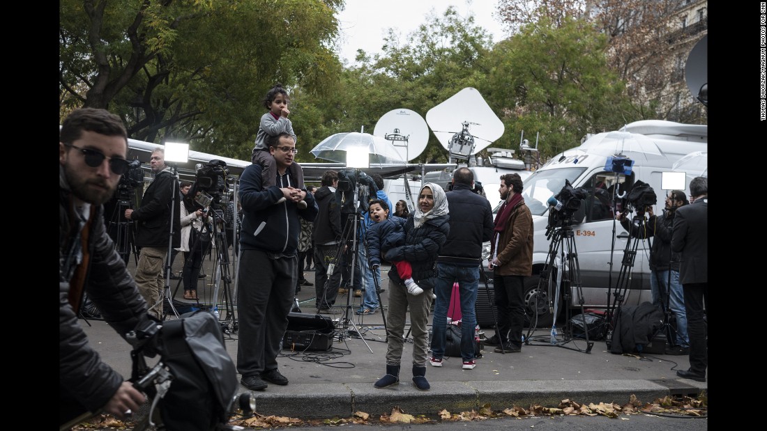 A family stands among TV crews set up on November 14 near the Bataclan.