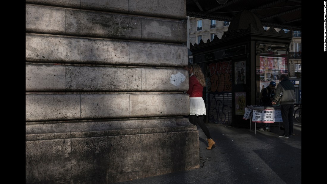 People walk past a man selling newspapers near the Barbes-Rochechouart Metro station on November 15. 