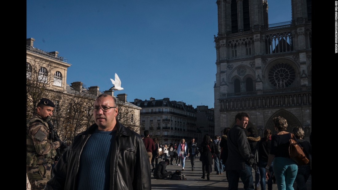 Tourists walk past Notre Dame on November 15 as the military and police patrol the area. 