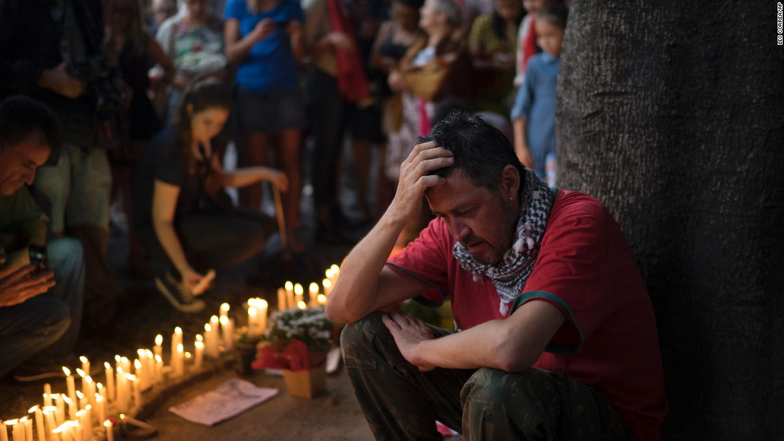 A man sits next to candles lit as homage to the victims of the deadly attacks in Paris at a square in Rio de Janeiro on November 15.