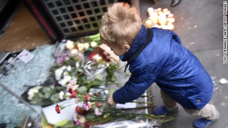 A boy lays flowers outside a Japanese restaurant next to the cafe &#39;La Belle Equipe&#39;, Rue de Charonne, in Paris on November 14.
