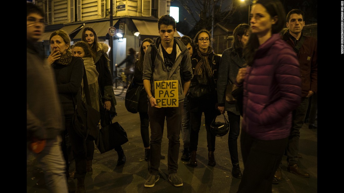 A young man in Paris on November 16 holds a sign that reads &quot;Not even afraid&quot; in the neighborhood of Le petit Cambodge, a restaurant that was hit in the attacks.