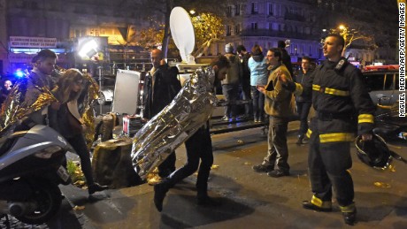 People wearing survival blankets walk from the Bataclan. 