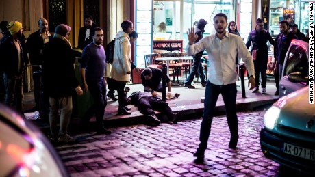 A crowd gathers outside Café Bonne Bière as a man lies on the pavement.