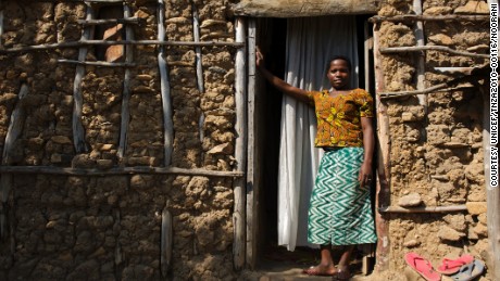 Christina John (14 years old) stands outside her house where she lives with her husband and her mother-in-law in Rebu village in Tarime district of Mara region in Tanzania. She was married when she was little over 13 years old. She managed to finish grade 7 before she was married off.
Every year approximately 100-150 girls (ranging between 9 and 15 years) are gathered for female genital mutilation ceremony. When Christine turned 12, her mother along with other women from village took Christina and her friends to a nearby village for female genital mutilation (FGM).

â??My mother had told me what would happen and she said it is a natural thing so I was not afraid. I did not realized how painful it will be. I donâ??t think it is right to circumcise girls because it is so painful. There are women who grow their nails especially scratch you with their long nails to remove the blood clots â?? it is so painful.â?

After the procedure girls return and stay home for one month to allow their wound to heal. Once healed, they are considered ready for marriage. The community holds a â??ngomaâ?? ceremony where men come to select their wife. 

â??My father told me I had to get married because that is what women do after they have been circumcised.â?

â??John gave my father 5 cows. My father bought me a few dishes. We got married after that and left to go live at Johnâ??s house. We live here with my mother-in-law and oldest brother-in-law.â?
â??I donâ??t know how old John is. When I ask him he wonâ??t tell me, he says, why do you need to know my age. My mother says that he is 26. He works as a day labourer and load stones.â?

â??My mother-in-law wants me to have six children, but how will I educate them, how will I provide for six children? My mother-in-law also says that I will get pregnant if I take traditional medicine. But I refuse to take this medicine. I want to have three children, but I want to wait until Iâ??m about 18 or 20.â?

â??I donâ??t 