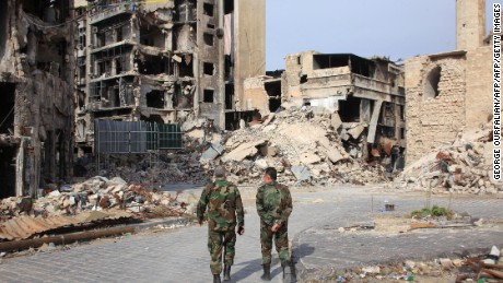 Syrian government forces walk on a heavily damaged street in the regime-controlled side of the northern city of Aleppo on November 9.