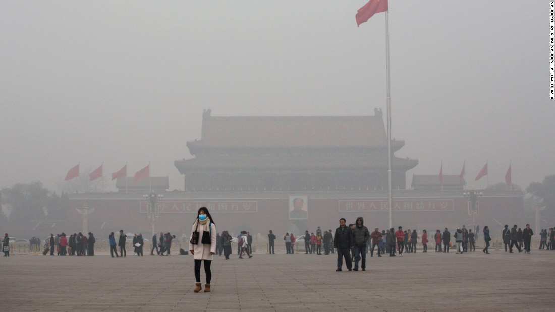 A Chinese woman protects herself with a mask as she walks past Tiananmen Square in smog-hit Beijing on November 30, 2015. Levels of PM 2.5, considered the most hazardous pollutant, crossed 600 units in Beijing, nearly 25 times the acceptable standard set by the World Health Organization. 