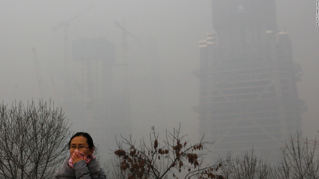 A woman protects herself from pollutants with a piece of cloth as she walks past a construction site on November 30 in Beijing.