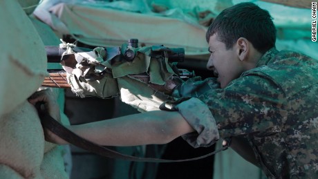 A Kurdish sniper takes position, his gun camouflaged.