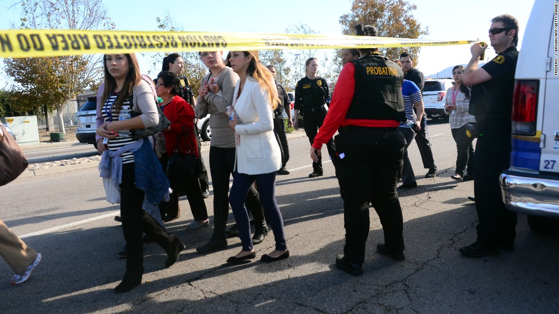 Police escort civilians away from the site of the shooting.