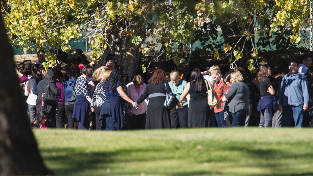 People pray on the San Bernardino Golf Course, across the street from where the shooting took place.