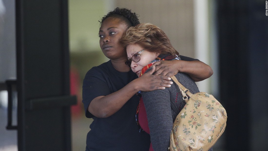 Two women embrace at a community center where family members were gathering to pick up people from the scene.