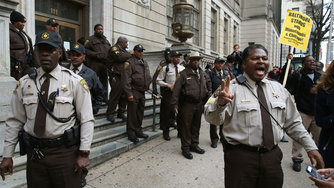Law enforcement officers try to calm down a crowd gathered in front of the courthouse on December 16. Gray died in April after sustaining a neck injury while in police custody. 