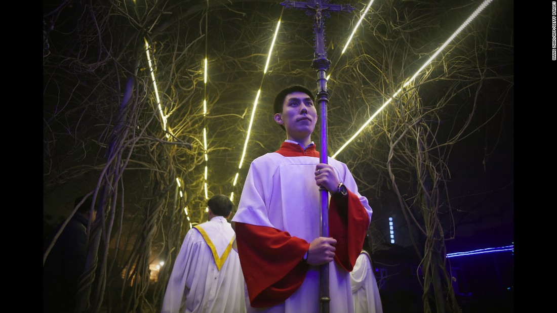 A cross-bearer attends a Christmas Eve Mass at a Catholic church in Beijing on Thursday.