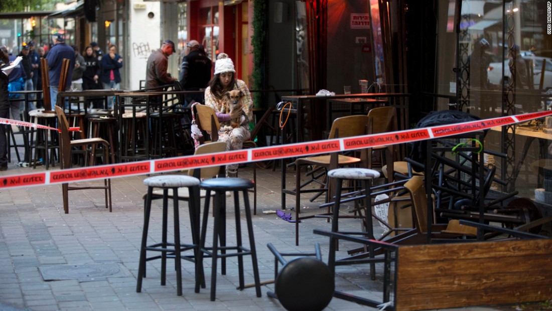 An eyewitness sits with her dog at the scene of &lt;a href=&quot;http://www.cnn.com/2016/01/01/middleeast/tel-aviv-pub-shooting/index.html&quot; target=&quot;_blank&quot;&gt;a shooting in Tel Aviv, Israel,&lt;/a&gt; on Friday, January 1. At least two people were killed and four were injured when an unidentified gunman opened fire on a group of people near a pub, authorities said.