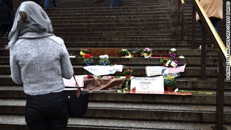 A woman looks at flowers and messages laid on steps in front of Cologne&#39;s main train station.