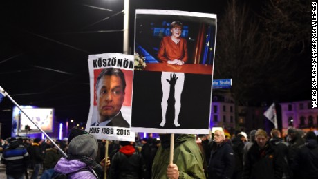 Protesters in Leipzig hold aloft posters depicting German Chancellor Angela Merkel being groped and of Hungarian PM Viktor Orban, known for his anti-migrant stance. The latter reads &quot;Thanks&quot; in Hungarian.