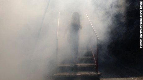 A woman walks through a haze of pesticide in  El Salvador.