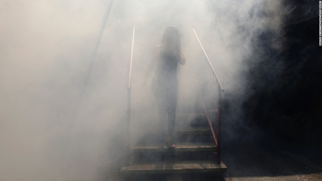 A woman walks through fumes as health ministry employees fumigate an area in Soyapango on Thursday, January 21.