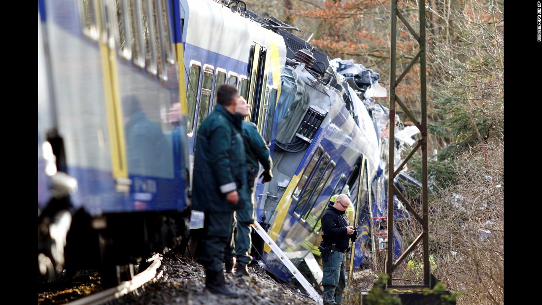 Police stand beside the trains as rescue personnel search the wreckage.