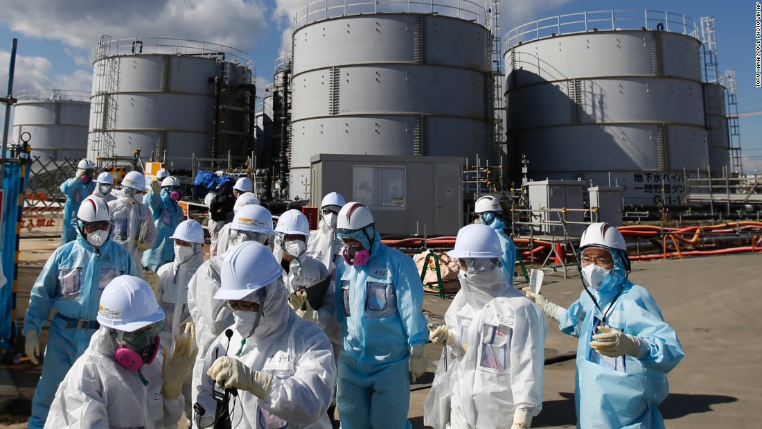 TEPCO employees, in blue protective suits, brief a press group in front of storage tanks for radioactive water on Februray 10.