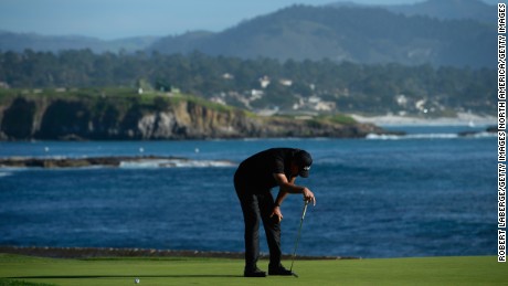 Phil Mickelson bows his head after seeing his birdie putt on 18 drift past the final hole. 