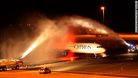 The plane carrying Pavlos Kontides taxies under a victory water arch laid on by the fire service after landing at Larnaca Airport.