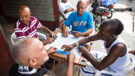 Men play dominoes on the sidewalk of Santo Domingo&#39;s Little Haiti neighborhood.