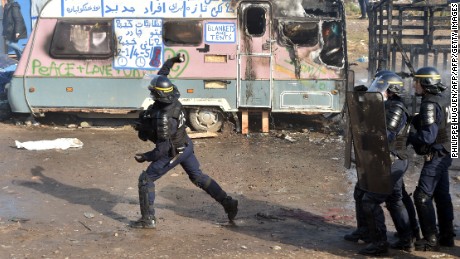 A police officer throws a tear gas canister during the dismantling of half of the &quot;Jungle&quot; migrant camp.