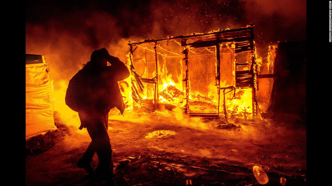 A migrant walks past a burning shack in the southern part of the &quot;Jungle&quot; migrant camp in Calais, France, in March 2016. Part of the camp was being demolished -- and the inhabitants relocated -- in response to unsanitary conditions at the site.