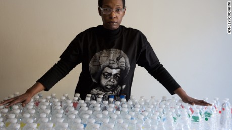 Gina Luster in her Flint, Michigan home with the total bottles of water it takes to get through a day