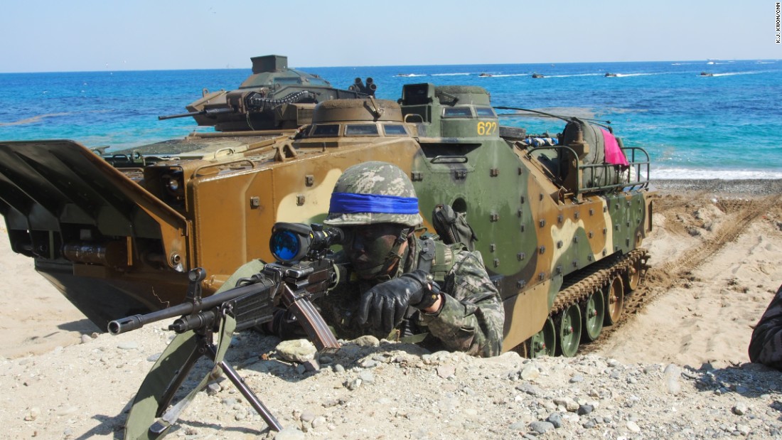 A South Korean Marine looks through his rifle&#39;s view finder on March 12 with an amphibious assault vehicle in the background. 