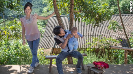 Xiao Rong, 16, (vas.) katselee, kun hänen 20-vuotias aviomiehensä Xiao Yong pitelee heidän 10 kuukauden ikäistä lastaan Menglan piirikunnassa, Yunnanin maakunnassa.