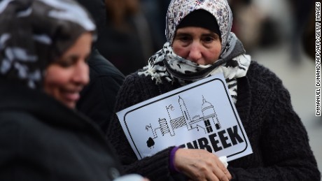 A woman holds a piece of paper reading &quot;Molenbeek&quot; during a candlelit vigil to the victims of the Paris attacks in Brussels.