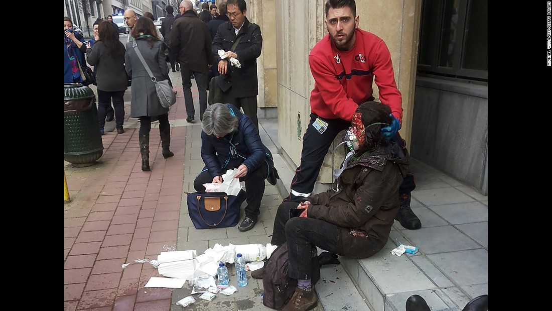 A private security guard helps a wounded woman outside the Maelbeek metro station.
