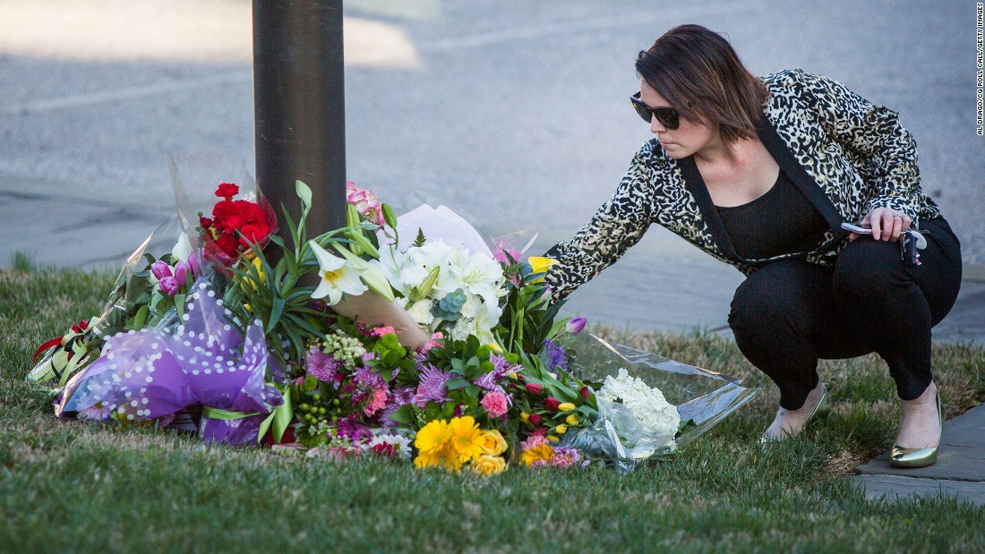 A woman leaves a bouquet of flowers at the base of the Belgium and European Union flags, which were flying at half-staff March 22 at the Belgian Embassy in Washington.